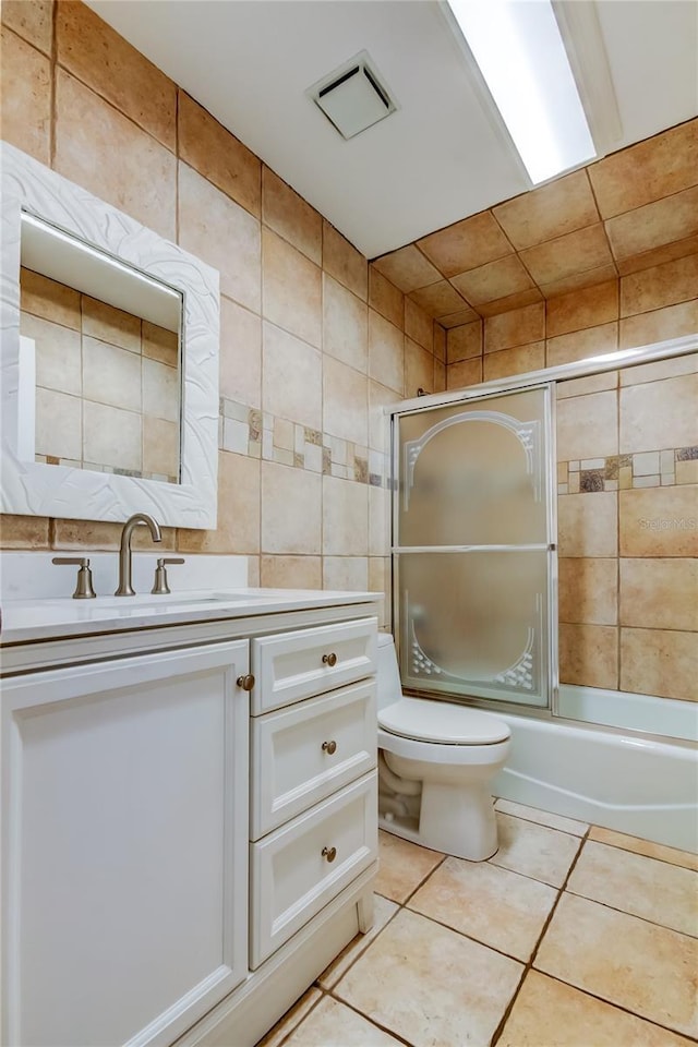 full bathroom featuring tile walls, shower / bath combination with glass door, vanity, toilet, and tile patterned floors