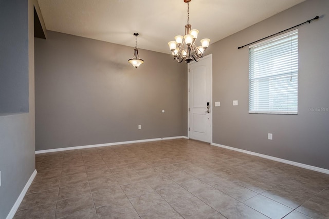 empty room with tile patterned flooring and a notable chandelier