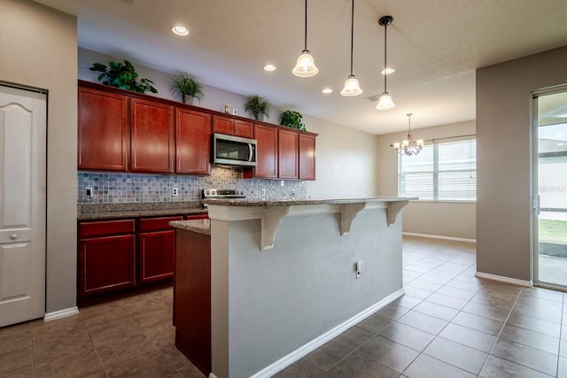 kitchen featuring hanging light fixtures, decorative backsplash, a kitchen bar, and a kitchen island