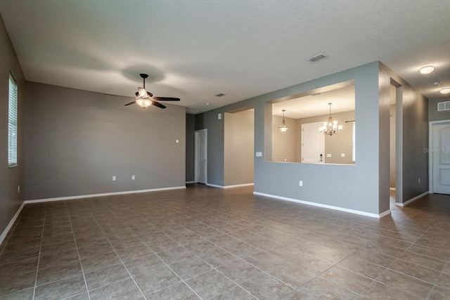 tiled empty room featuring ceiling fan with notable chandelier and a textured ceiling