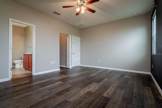 unfurnished bedroom featuring connected bathroom, dark wood-type flooring, and ceiling fan