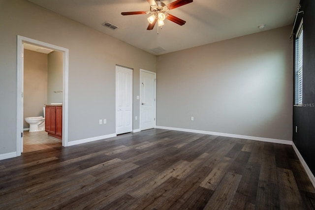 unfurnished bedroom featuring connected bathroom, dark hardwood / wood-style floors, and ceiling fan