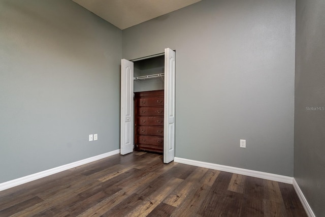 unfurnished bedroom with dark hardwood / wood-style flooring and a closet