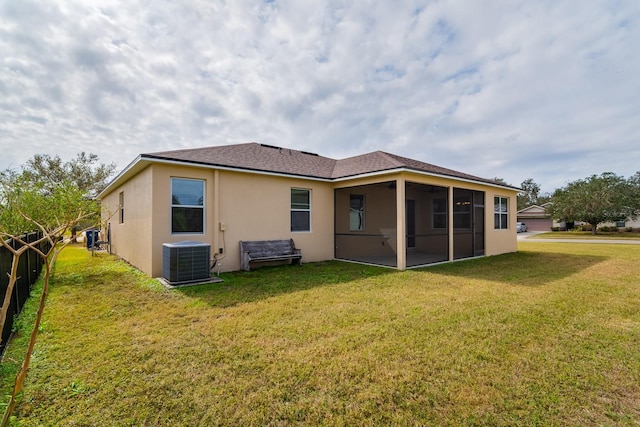 rear view of property with a sunroom, central AC unit, and a lawn