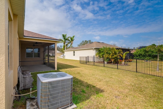 view of yard with ceiling fan, central AC unit, and a sunroom