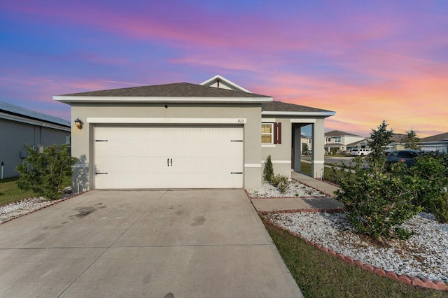 single story home featuring stucco siding, driveway, a garage, and roof with shingles