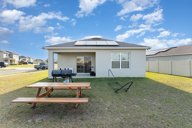 rear view of house featuring a yard and solar panels