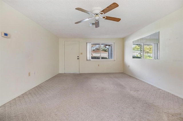 empty room featuring a textured ceiling, ceiling fan, and carpet flooring