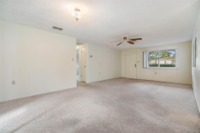 empty room with ceiling fan, light colored carpet, and a textured ceiling