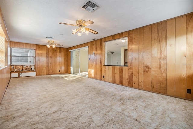 carpeted spare room with ceiling fan and wood walls