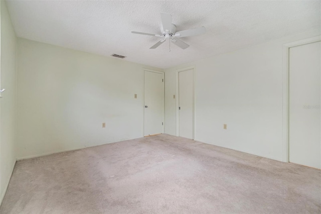 carpeted spare room featuring ceiling fan and a textured ceiling