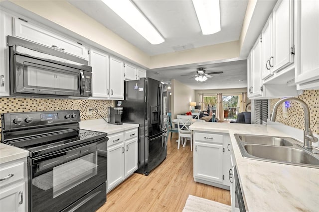 kitchen with light wood-type flooring, white cabinets, sink, and black appliances