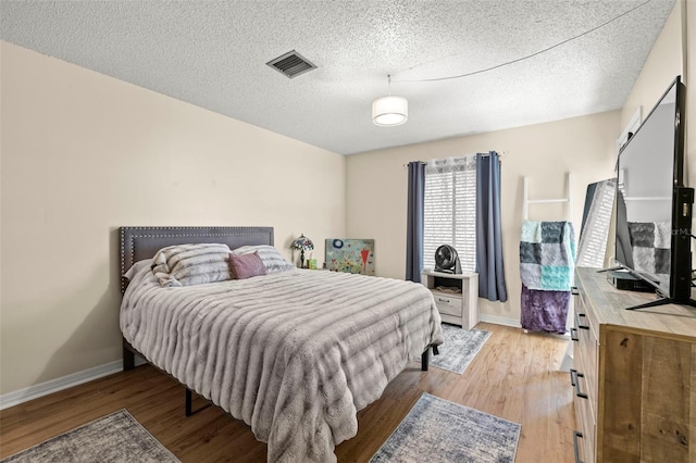 bedroom featuring a textured ceiling and light hardwood / wood-style flooring