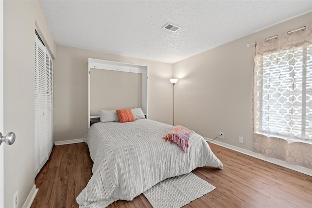 bedroom featuring hardwood / wood-style flooring, a closet, and a textured ceiling