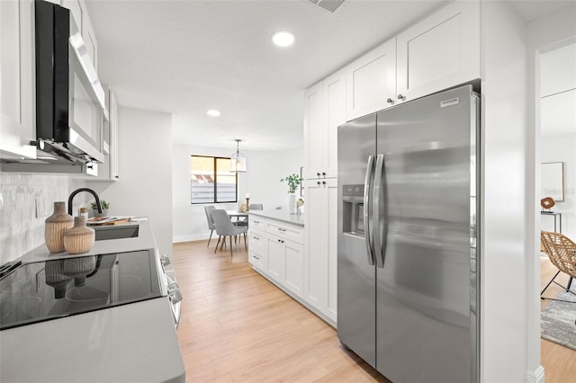 kitchen featuring decorative backsplash, stainless steel appliances, white cabinets, and light wood-type flooring