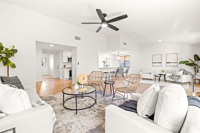 living room featuring vaulted ceiling, ceiling fan, and light hardwood / wood-style floors