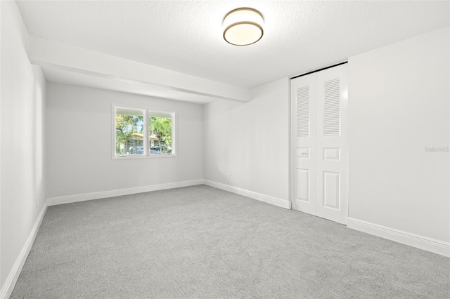 carpeted spare room with a textured ceiling