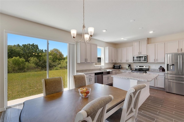 kitchen with pendant lighting, stainless steel appliances, a center island, and white cabinets