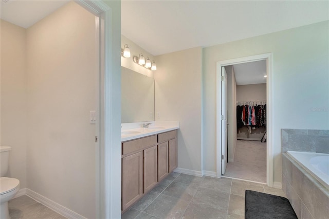 bathroom featuring vanity, tiled bath, and toilet