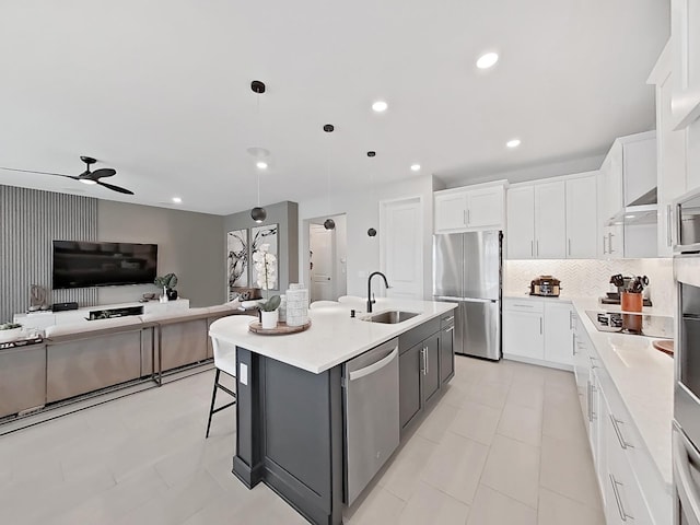 kitchen with white cabinetry, appliances with stainless steel finishes, a center island with sink, and decorative light fixtures