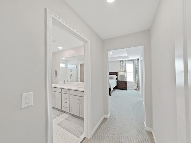 corridor with sink and light colored carpet