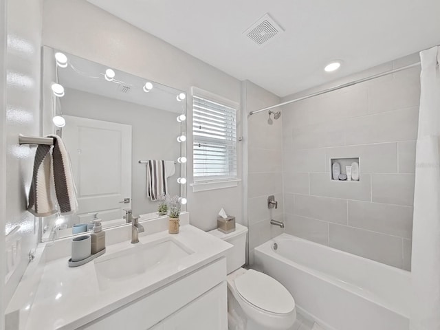 full bathroom with tiled shower / bath, vanity, and toilet