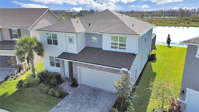 view of front of home with a garage, a front lawn, and a water view