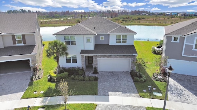 view of front of house featuring a garage, a water view, and a front lawn