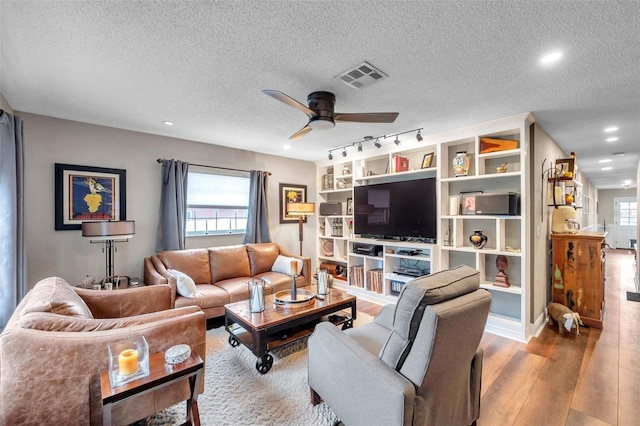 living room with wood-type flooring, rail lighting, a textured ceiling, and ceiling fan