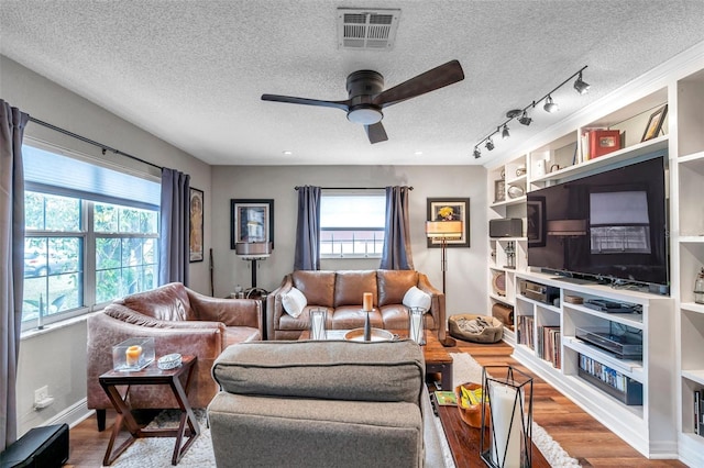 living room featuring wood-type flooring, track lighting, a textured ceiling, and ceiling fan