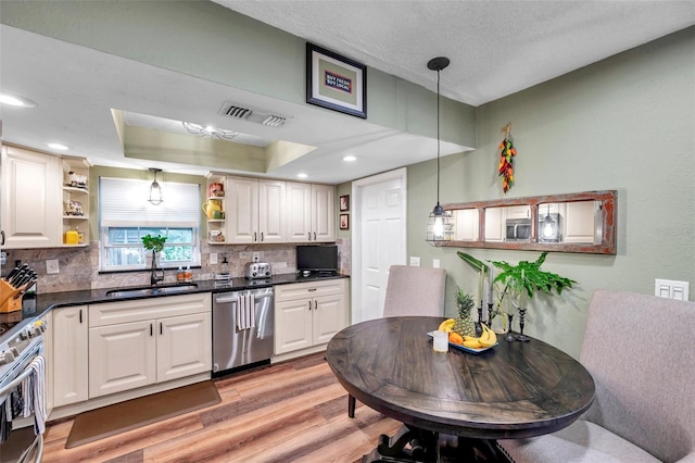 kitchen with white cabinetry, appliances with stainless steel finishes, sink, and a tray ceiling