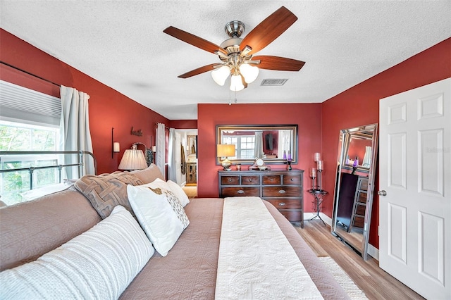 bedroom with ceiling fan, a textured ceiling, and light hardwood / wood-style floors