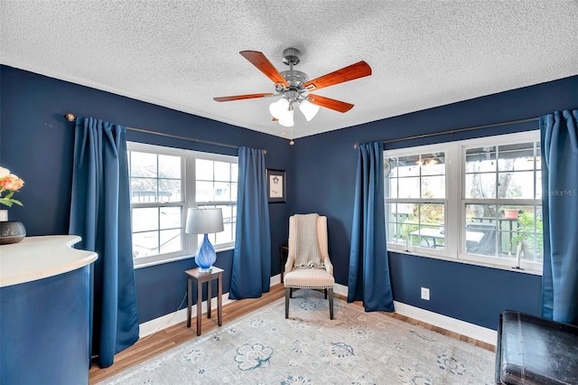 sitting room with ceiling fan, hardwood / wood-style floors, and a textured ceiling