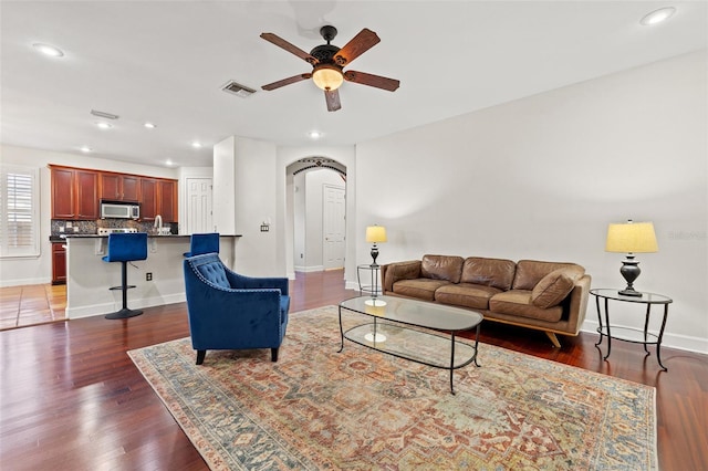 living room featuring ceiling fan and dark hardwood / wood-style flooring