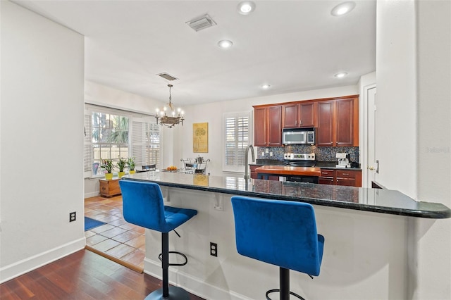 kitchen with stainless steel appliances, dark hardwood / wood-style flooring, a breakfast bar, decorative light fixtures, and tasteful backsplash