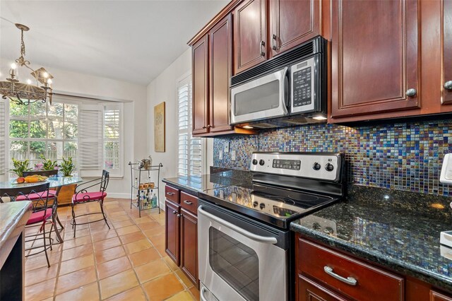 kitchen with stainless steel appliances, decorative light fixtures, a notable chandelier, tasteful backsplash, and dark stone countertops