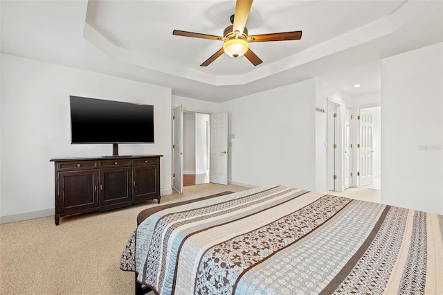 carpeted bedroom featuring ceiling fan and a tray ceiling