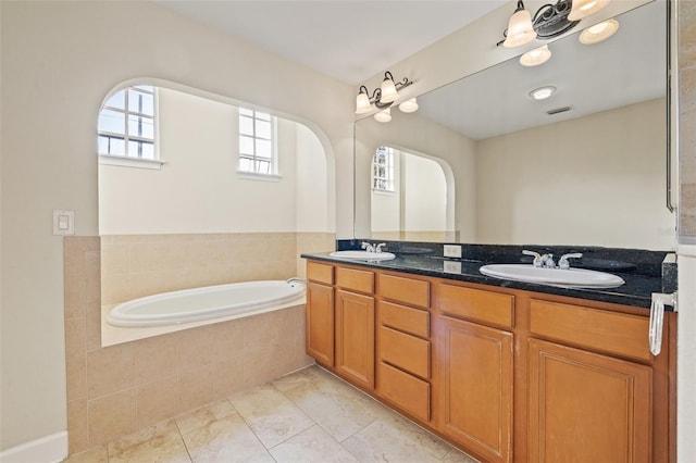 bathroom with vanity, tile patterned flooring, and tiled tub