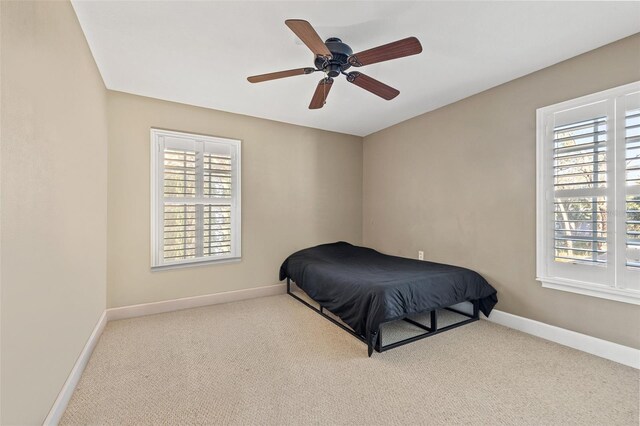 carpeted bedroom with ceiling fan and multiple windows