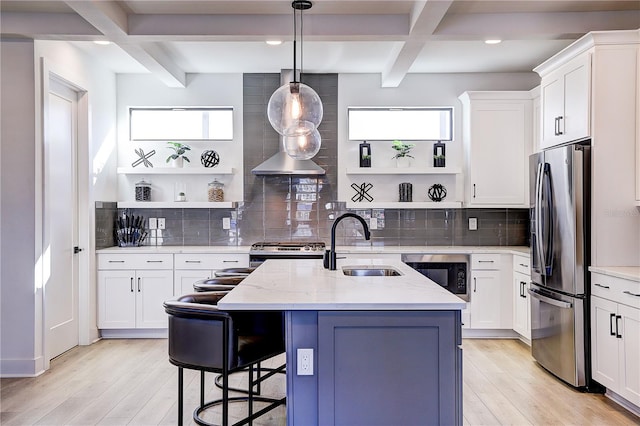 kitchen with white cabinetry, stainless steel appliances, light stone countertops, and an island with sink