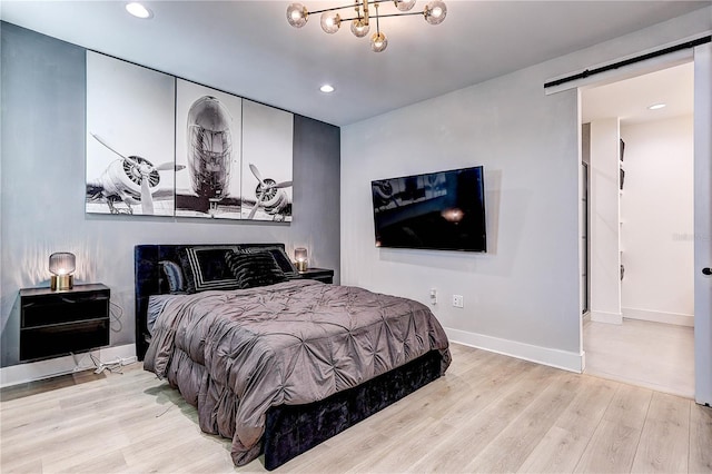 bedroom with a barn door and light wood-type flooring