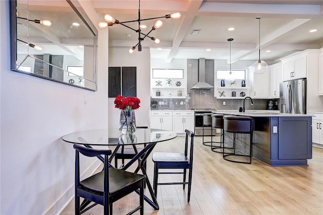 dining space featuring sink, coffered ceiling, light hardwood / wood-style floors, and beam ceiling