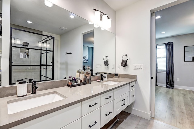 bathroom featuring hardwood / wood-style flooring, tiled shower, and vanity