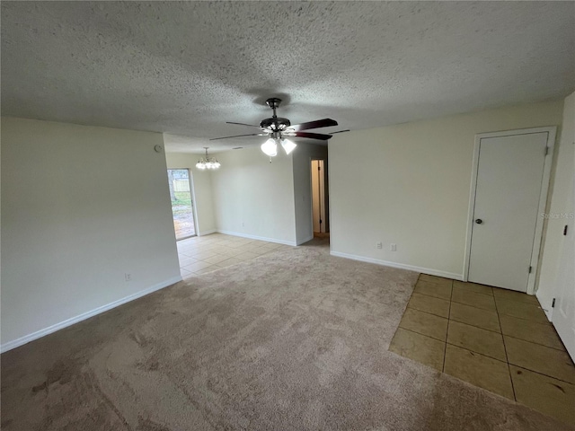 carpeted spare room featuring ceiling fan with notable chandelier and a textured ceiling