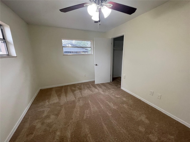 unfurnished bedroom with dark colored carpet, ceiling fan, and a closet