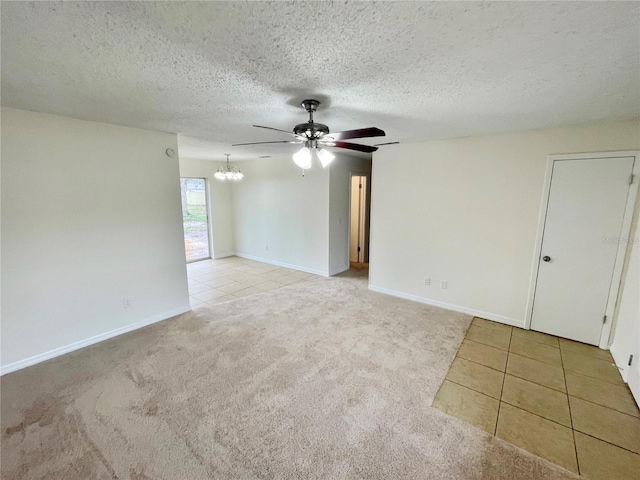 empty room with ceiling fan with notable chandelier, light colored carpet, and a textured ceiling