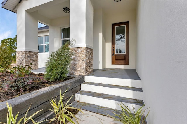 doorway to property featuring stone siding and stucco siding