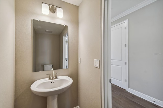 bathroom featuring wood-type flooring, crown molding, and toilet