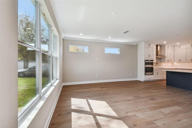 unfurnished living room featuring crown molding and light hardwood / wood-style floors