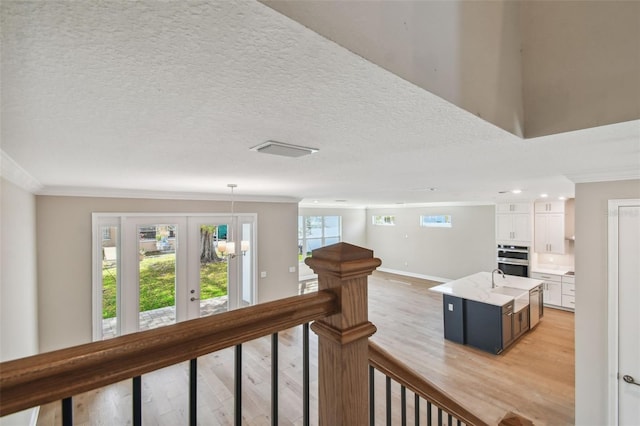 corridor with crown molding, light hardwood / wood-style floors, and a textured ceiling